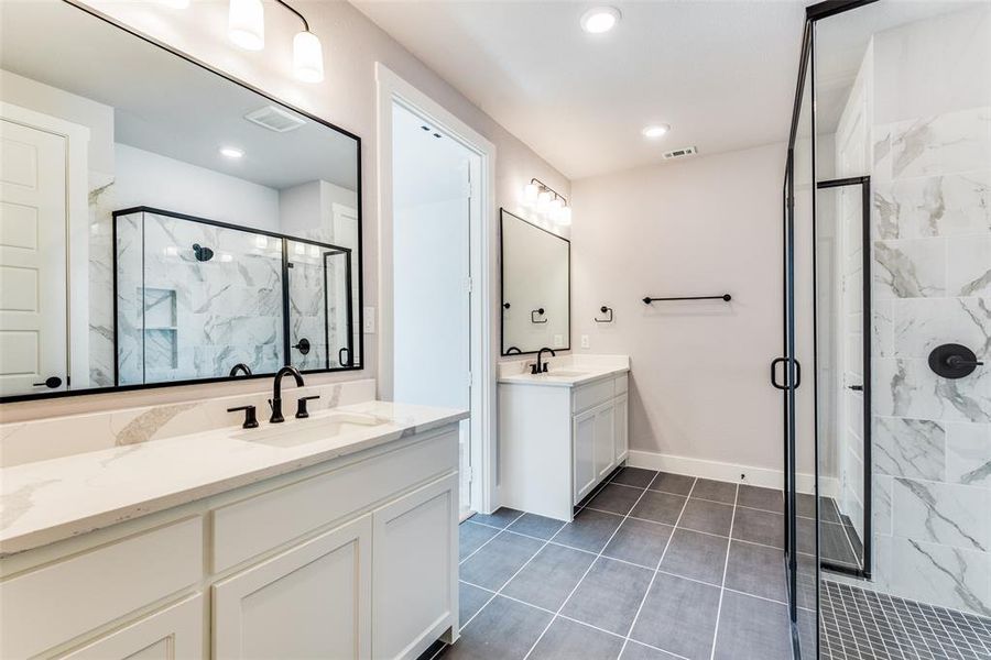 Bathroom featuring a shower with shower door, tile patterned flooring, and double vanity