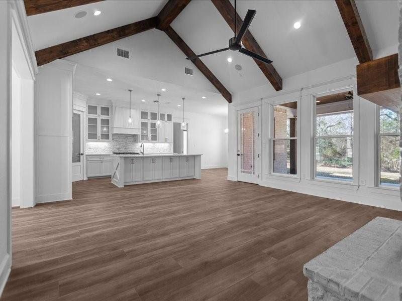 Unfurnished living room with beam ceiling, recessed lighting, dark wood finished floors, a ceiling fan, and high vaulted ceiling