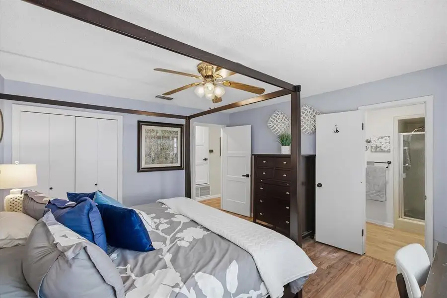 Bedroom with wood-finish flooring, ceiling fan with integrated lighting, and light blue wall color