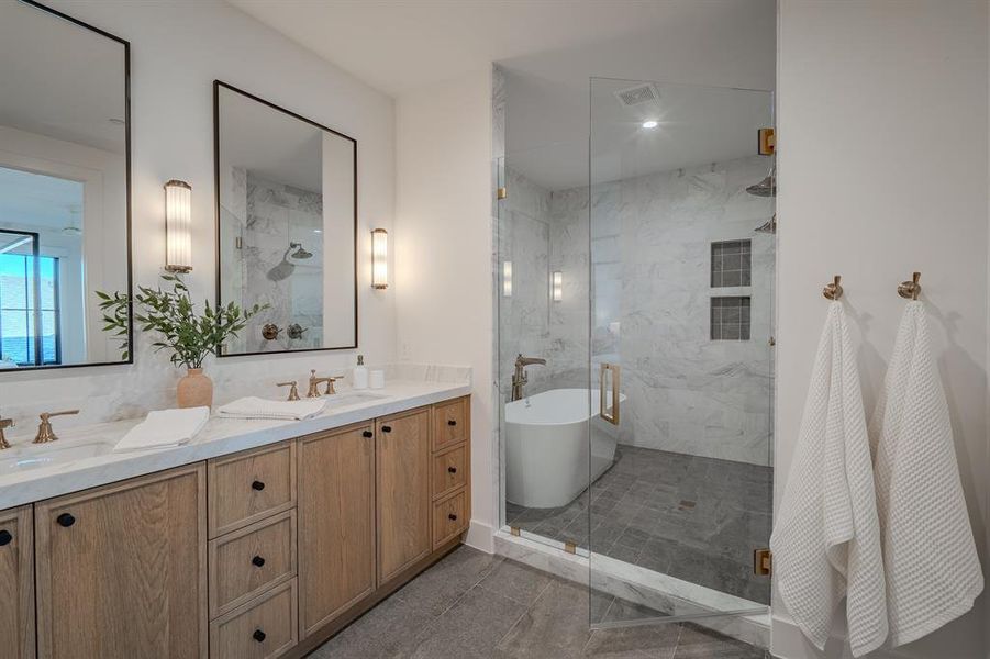 Full bath with a marble finish shower, double vanity, a freestanding bath, and dark tile patterned flooring Full bath with a marble finish shower, double vanity, a freestanding bath, and dark tile patterned flooring