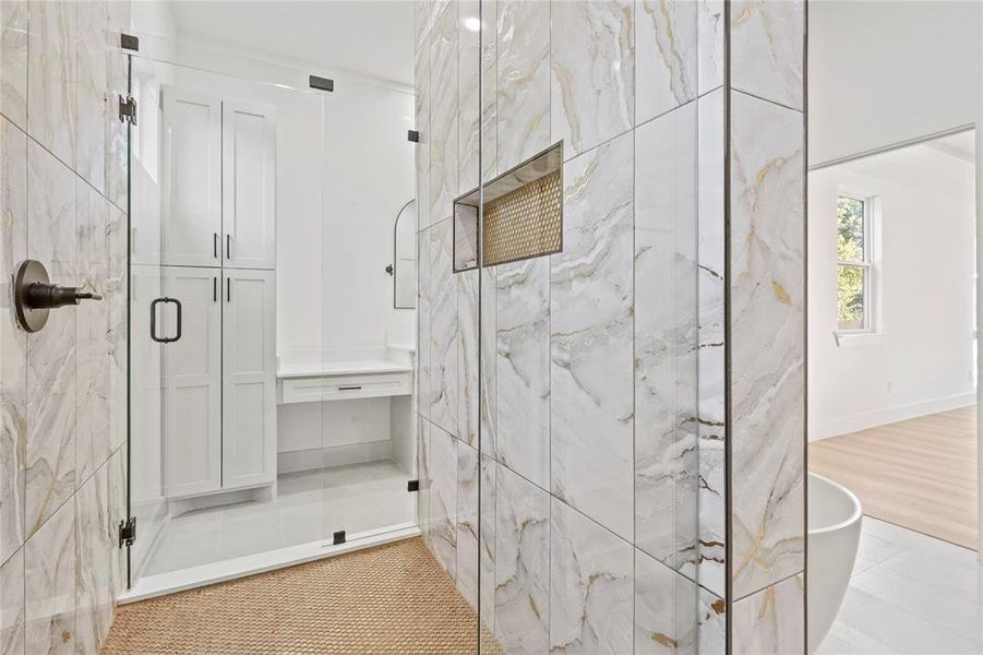 Bathroom featuring a marble finish shower and tile walls