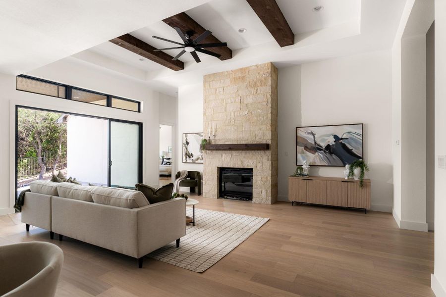 A striking stone fireplace and exposed beams define this inviting living area, complemented by abundant natural light.