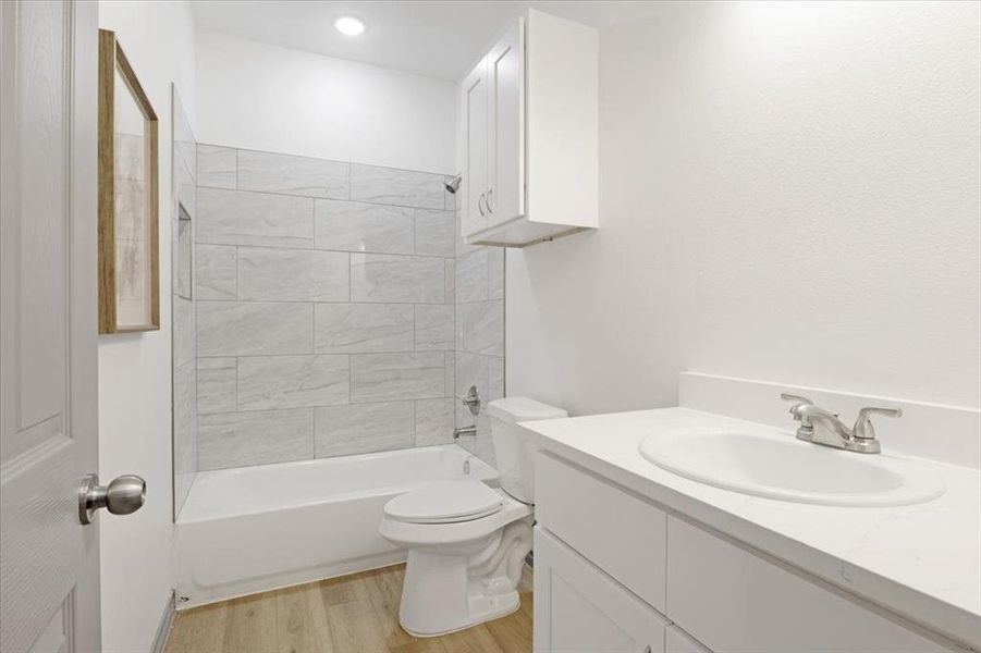 Full bathroom featuring toilet, wood-type flooring, vanity, and tiled shower / bath combo