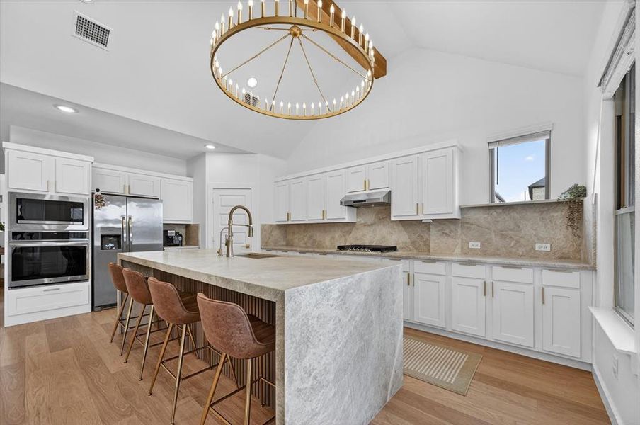 Kitchen featuring a vaulted ceiling and an oversized island with an integrated sink