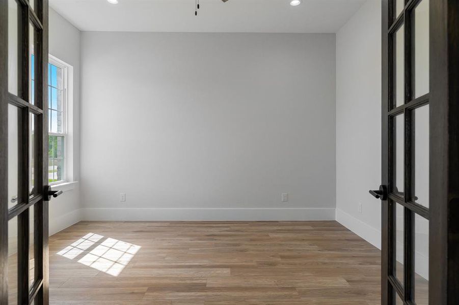 Office space, featuring french doors, light wood vinyl floors, recessed lighting, and a ceiling fan.