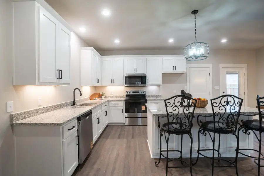 Kitchen featuring appliances with stainless steel finishes, a sink, a breakfast bar area, white cabinets, and recessed lighting Kitchen featuring appliances with stainless steel finishes, a sink, a breakfast bar area, white cabinets, and recessed lighting