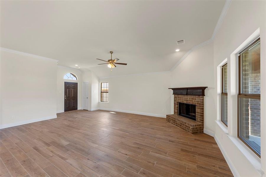 Unfurnished living room with a fireplace, wood finish floors, ceiling fan, recessed lighting, and crown molding