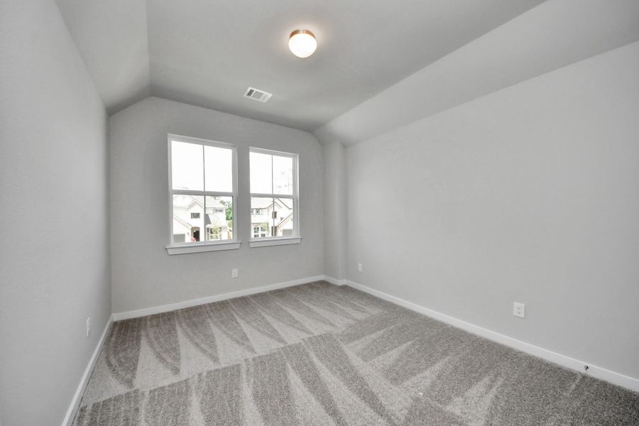 Secondary bedroom features plush carpeting, large windows that let in plenty of natural light, bright paint, and spacious closets. Sample photo of completed home with similar floor plan. Actual colors and selections may vary.