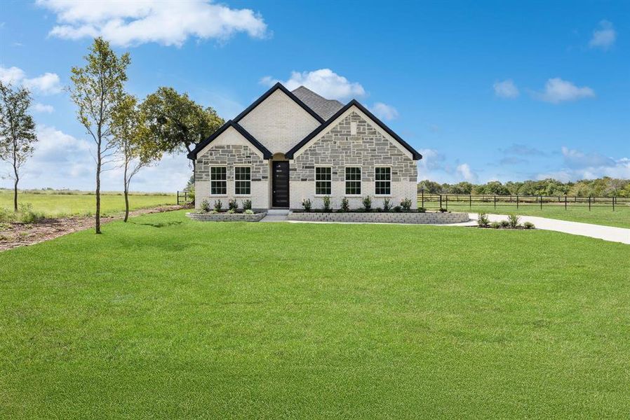French country home with stone siding, a front yard, a view of rural / pastoral area, and brick siding French country home with stone siding, a front yard, a view of rural / pastoral area, and brick siding