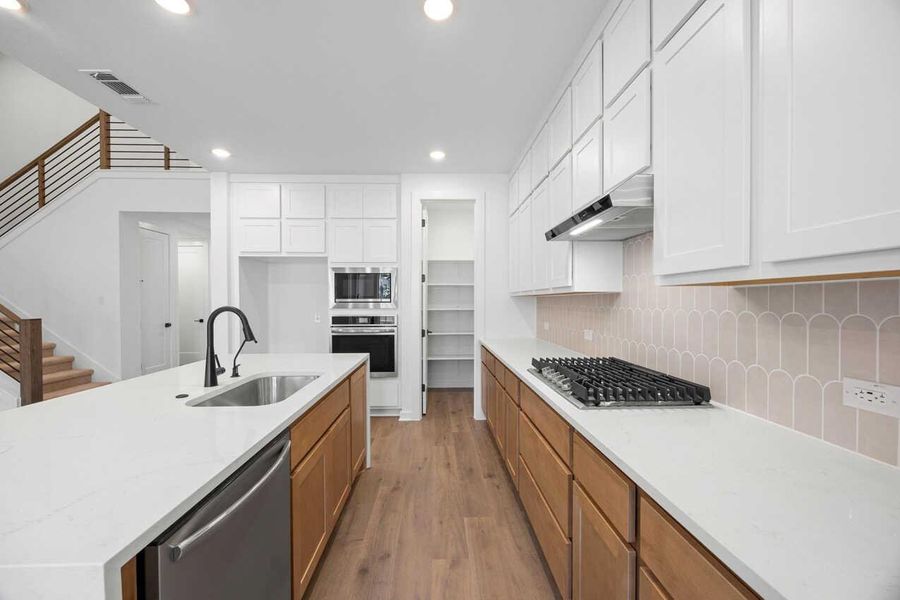 Kitchen with dark wood-type flooring, recessed lighting, light stone counters, appliances with stainless steel finishes, and decorative backsplash Kitchen with dark wood-type flooring, recessed lighting, light stone counters, appliances with stainless steel finishes, and decorative backsplash