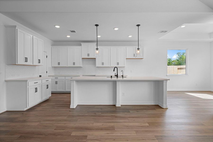 This light and bright kitchen features a large quartz island, white cabinets, a large sink overlooking your family room, recessed lighting, and beautiful backsplash. This light and bright kitchen features a large quartz island, white cabinets, a large sink overlooking your family room, recessed lighting, and beautiful backsplash.