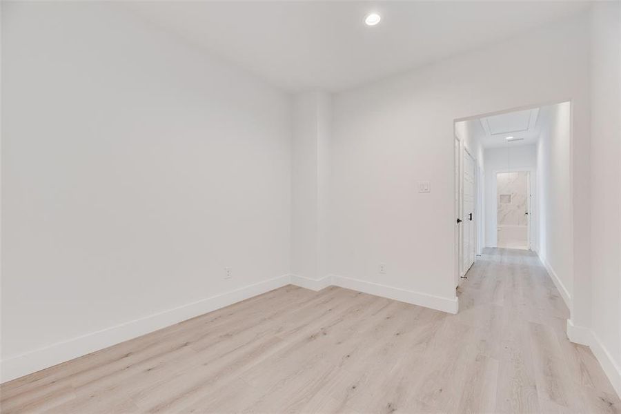 Empty room with light wood-type flooring, attic access, and recessed lighting