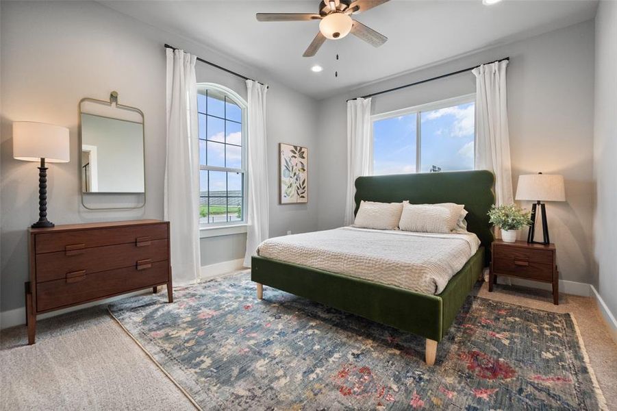 Primary bedroom with ceiling fan and carpet