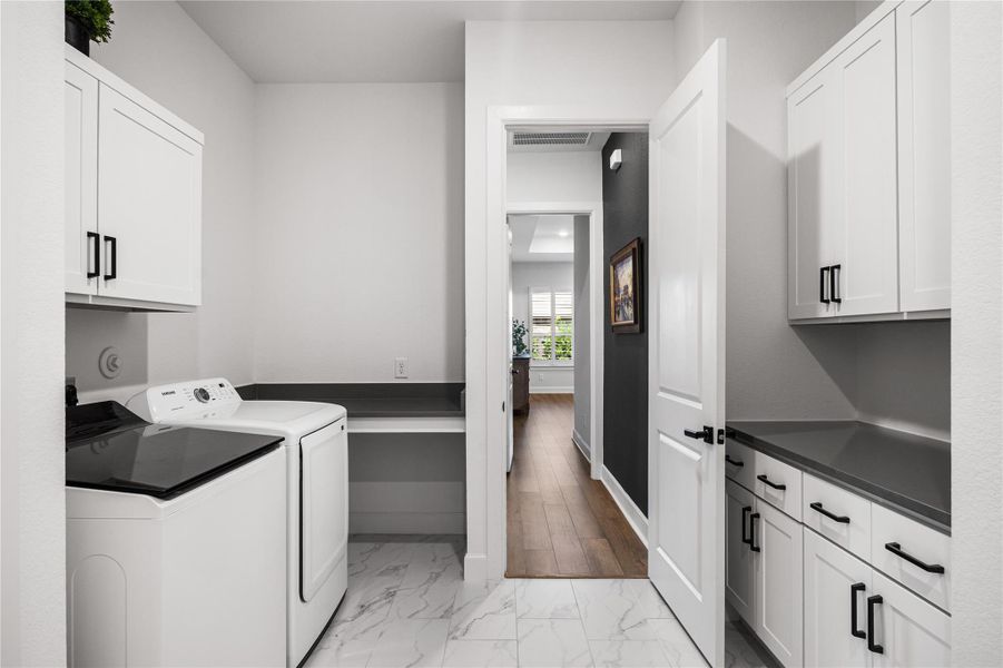 Well-appointed laundry room with built-in cabinetry, a convenient drop-off area, and dedicated folding space.