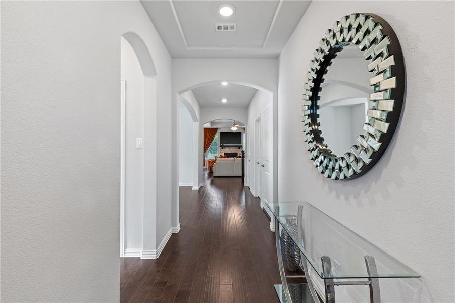 Hallway featuring wood-finish flooring, recessed lighting, and arched doorways