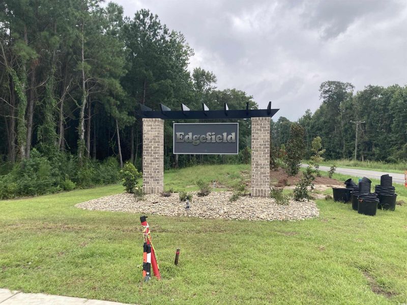 Community / neighborhood sign featuring a yard