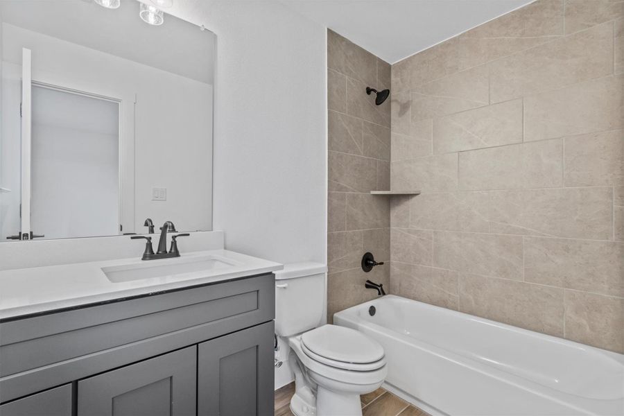 Full bathroom featuring toilet, tiled shower / bath combo, hardwood / wood-style floors, and vanity