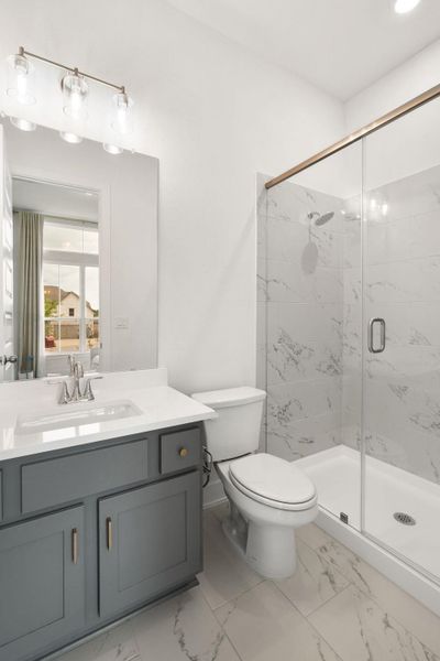 Modern bath features a sophisticated vanity with ample storage, beside a pristine tiled shower.