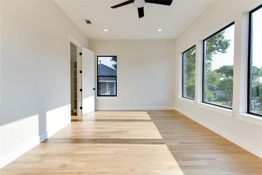 Unfurnished room featuring ceiling fan, light wood-type flooring, and plenty of natural light