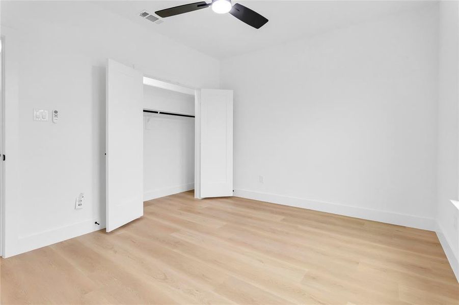 Unfurnished bedroom featuring light wood-style flooring, a closet, and ceiling fan