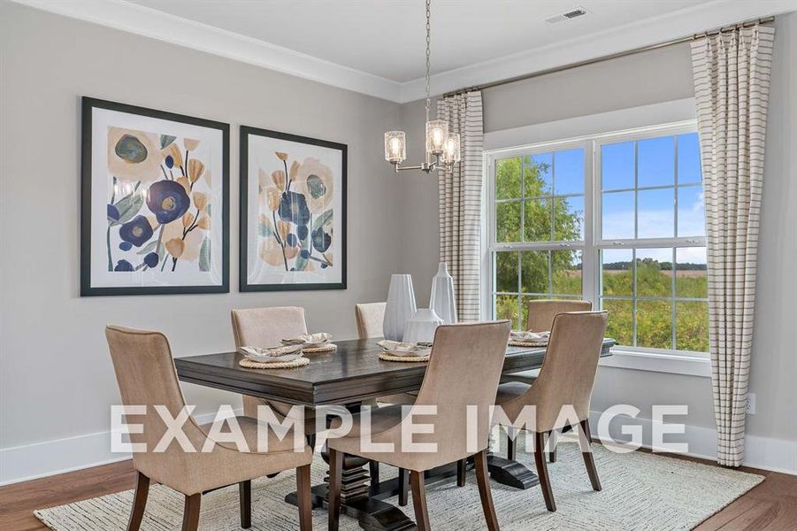 Dining space with wood-type flooring, ornamental molding, and an inviting chandelier