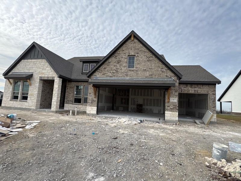 View of front of home featuring brick siding, a patio, and roof with shingles