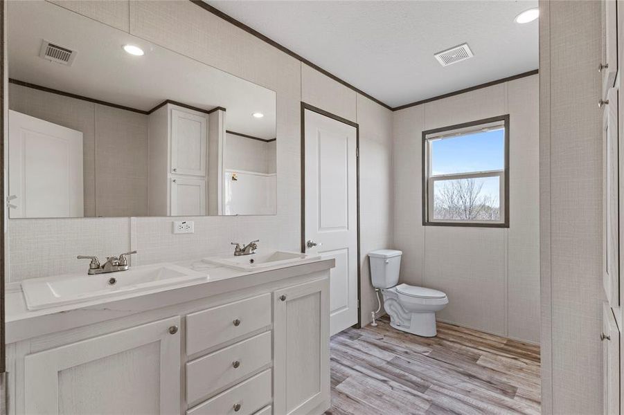 Bathroom featuring double vanity, ornamental molding, light wood-style flooring, recessed lighting, and tasteful backsplash