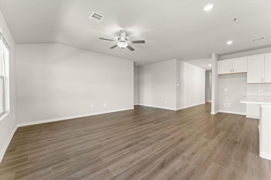 Unfurnished living room with ceiling fan, lofted ceiling, dark wood-type flooring, and a healthy amount of sunlight