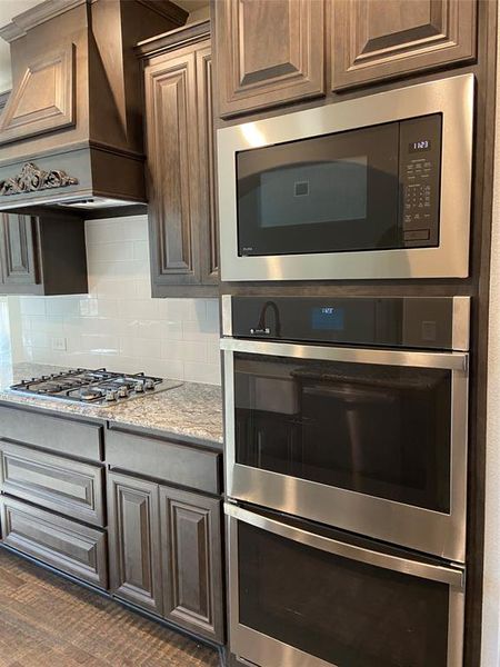 Kitchen with stainless gas cooktop, built-in double ovens with microwave, and dishwasher