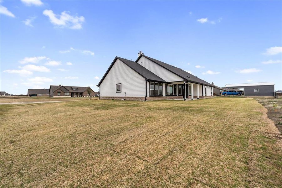 View of side of property featuring a lawn and a patio area