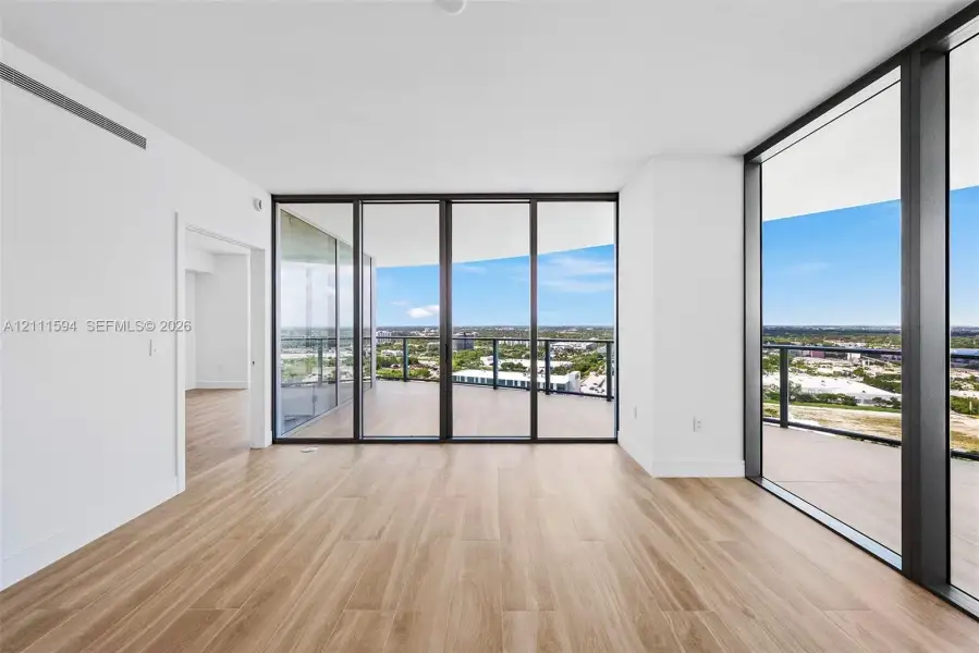 Floor-to-ceiling glass sliding doors, expansive wraparound terrace, wood-finish flooring, and minimalist white interior walls Floor-to-ceiling glass sliding doors, expansive wraparound terrace, wood-finish flooring, and minimalist white interior walls
