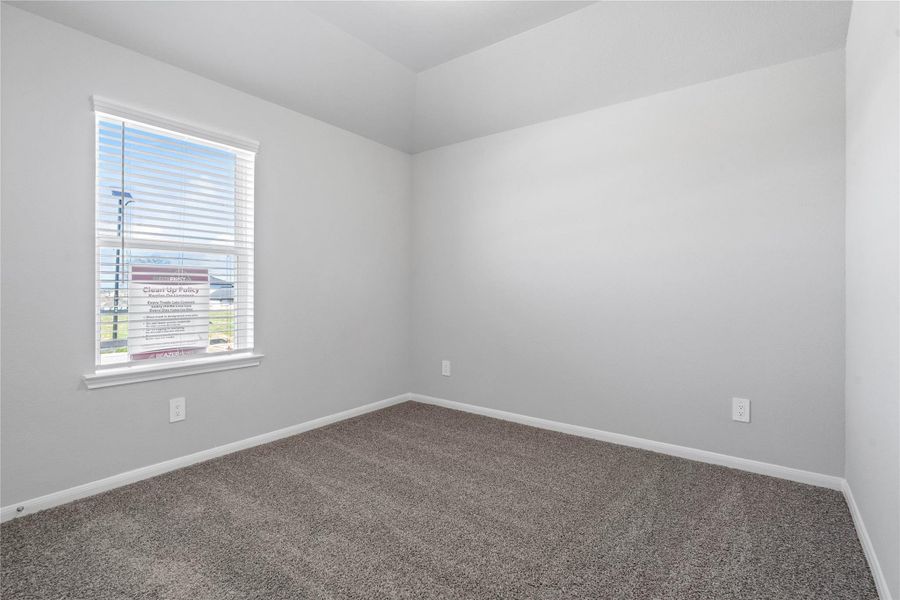 Tucked peacefully in the front of this home is a secondary bedroom perfect for guests or a quiet home office. It features soft plush carpeting, a window with fitted blinds, sloped ceiling, and ample sized closet space.