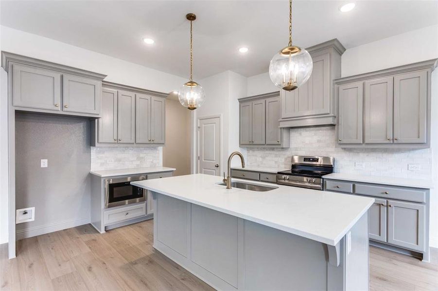Kitchen with sink, gray cabinetry, stainless steel electric range oven, black microwave, and pendant lighting