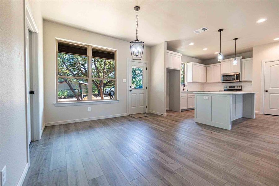 Kitchen with light countertops, white cabinetry, appliances with stainless steel finishes, light wood finished floors, and recessed lighting