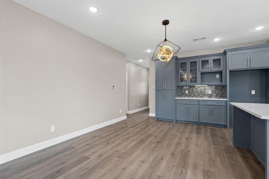 Kitchen featuring glass insert cabinets, decorative backsplash, light wood finished floors, recessed lighting, and decorative light fixtures Kitchen featuring glass insert cabinets, decorative backsplash, light wood finished floors, recessed lighting, and decorative light fixtures