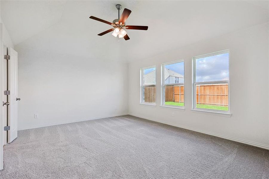 Carpeted spare room featuring ceiling fan and vaulted ceiling