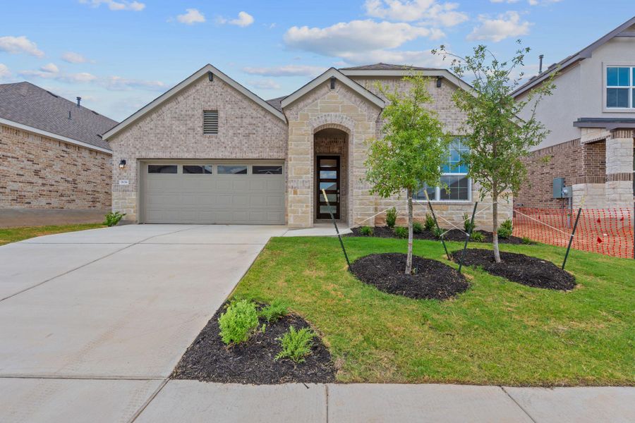 View of front facade featuring a garage, stone siding, driveway, and a front lawn View of front facade featuring a garage, stone siding, driveway, and a front lawn