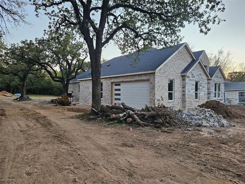 View of property exterior featuring brick siding, a shingled roof, an attached garage, and driveway View of property exterior featuring brick siding, a shingled roof, an attached garage, and driveway