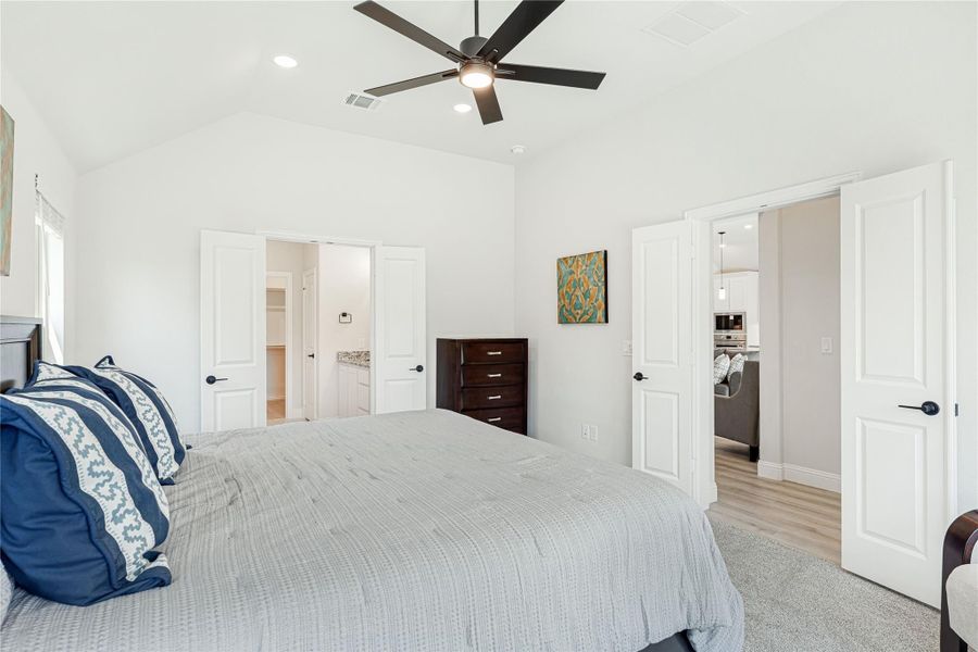 Bedroom with vaulted ceiling, ceiling fan, and doors leading to walk-in closet and bathroom
