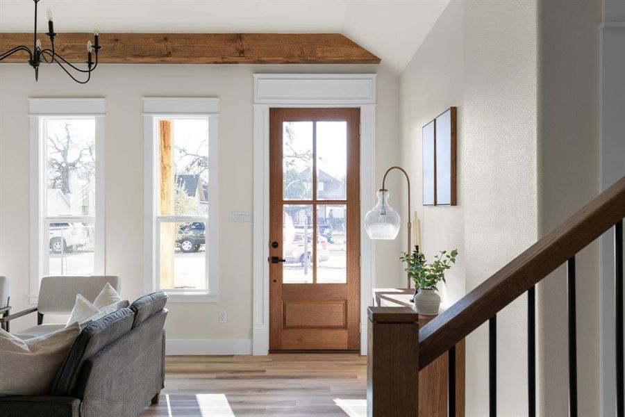 Entrance foyer featuring light hardwood / wood-style flooring, lofted ceiling, and an inviting chandelier