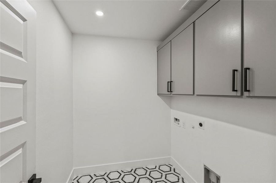 Clothes washing area with cabinets, electric dryer hookup, washer hookup, and light tile patterned flooring