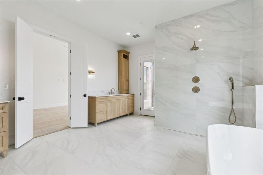 Incredible ensuite bath with separate vanities, a double shower, and soaking tub.