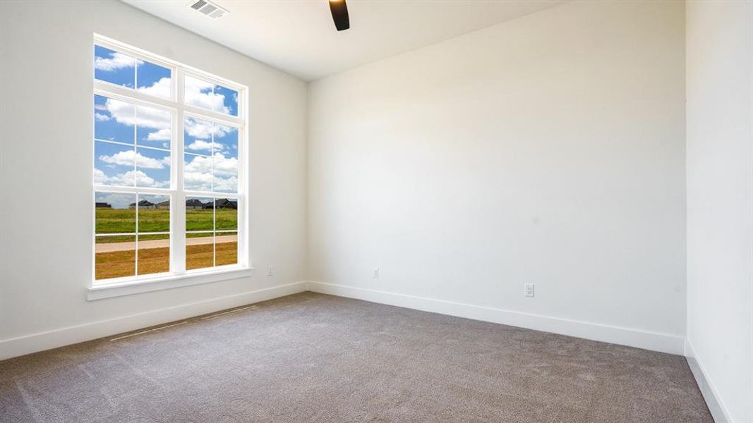 Carpeted spare room featuring ceiling fan