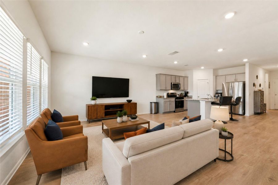 Living area showcasing recessed lighting, rich hardwood flooring and outdoor access.