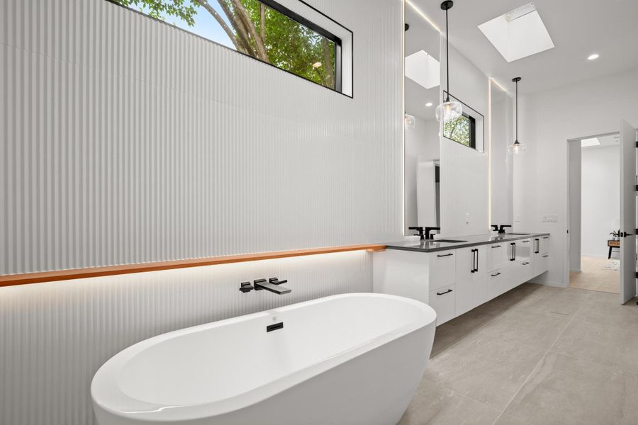 Full bathroom featuring double vanity, a skylight, and a freestanding bath