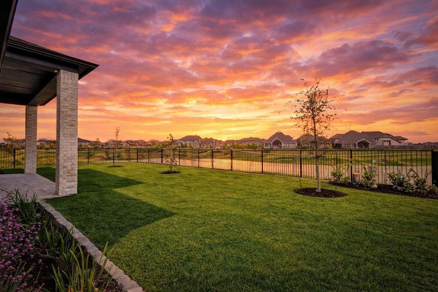 This fenced backyard offers an expansive lawn and a covered stone patio with views of the community water feature. The western exposure provides unobstructed views of vibrant sunsets across the horizon.
