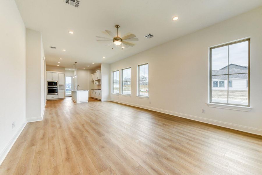 Unfurnished living room with a ceiling fan, healthy amount of natural light, recessed lighting, and light wood-style floors