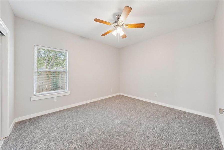 Carpeted spare room with baseboards and ceiling fan
