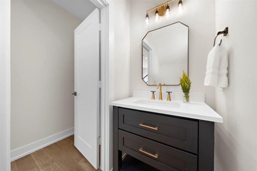 Modern touches abound in the first floor half bath including brass and black fixtures and a sleek octagonal mirror.