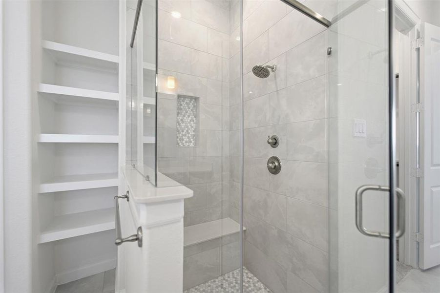Glass-enclosed shower with a built-in bench, rain showerhead, and brushed nickel fixtures